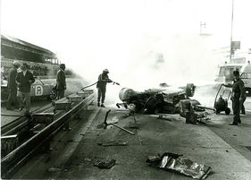 Herbert Linge als Feuerwehrmann mit Löschkanone 1972 am Nürburgring, rechts das Ferrari-Wrack von Herbert Müller