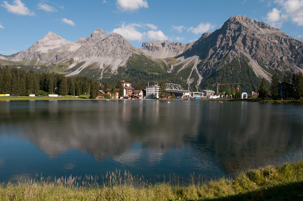 Arosa am Abend, die Fahrzeuge stehen im Fahrerlager, das Bergpanorama spiegelt sich im See – Impressionen von der Arosa ClassicCar 2013
