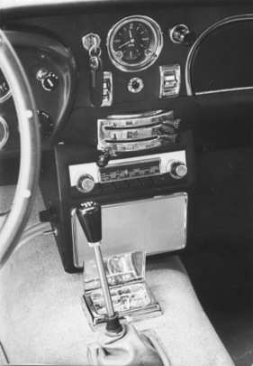 Aston Martin DB 5 Vantage (1965) - Mittelkonsole mit Uhr, Radio und Schaltern für die elektrischen Fensterheber