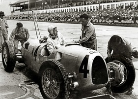 Auto Union Typ C (1936) - Boxenstopp mit Reifenwechsel an Rosemeyers Wagen beim Großen Preis von Deutschland am 26. Juli 1936 - hinten Ferdinand Porsche mit zwei Stoppuhren