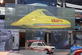 Banner mit einem überlebensgrossen Abbild des Abarth-Rekordwagens von 1956 – Ausstellung "75 Jahre Abarth" in der Autoworld Brüssel Banner mit einem überlebensgrossen Abbild des Abarth-Rekordwagens von 1956 – Ausstellung "75 Jahre Abarth" in der Autoworld Brüssel