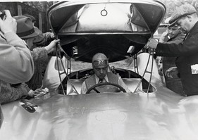 Bernd Rosemeyer mit Jacket und Krawatte bei einer Testfahrt auf der Berliner Avus im April 1937