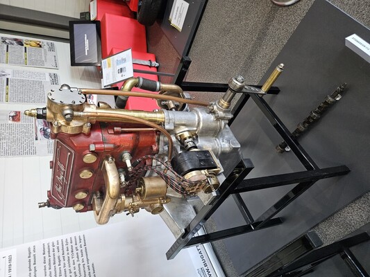 Image: Bugatti T13 (1910) — The brand's first mass-produced engine; the red cylinder block bears the company founder's signature, and in front of it, the main shaft is displayed as a separate exhibit
