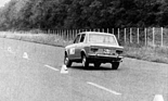 Das kurvenäussere Rad des Fiat 128 (1969) knickt in den positiven Sturz ein, während das kurveninnere Rad leicht vom Boden abhebt.