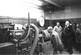 Der 16-Zylindermotor auf dem Leistungsprüfstand unter den interessierten Augen des ehemaligen Leiters des Rennwagenbaus, Robert Eberan-Eberhorst und des Rennmechanikers Ludwig Sebastian Der 16-Zylindermotor auf dem Leistungsprüfstand unter den interessierten Augen des ehemaligen Leiters des Rennwagenbaus, Robert Eberan-Eberhorst und des Rennmechanikers Ludwig Sebastian