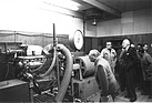 Der 16-Zylindermotor auf dem Leistungsprüfstand unter den interessierten Augen des ehemaligen Leiters des Rennwagenbaus, Robert Eberan-Eberhorst und des Rennmechanikers Ludwig Sebastian