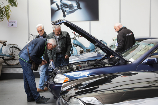 Der Motorraum eines R129 wird genau inspiziert - Versteigerung der Oldtimer Galerie Toffen am 22. März 2025