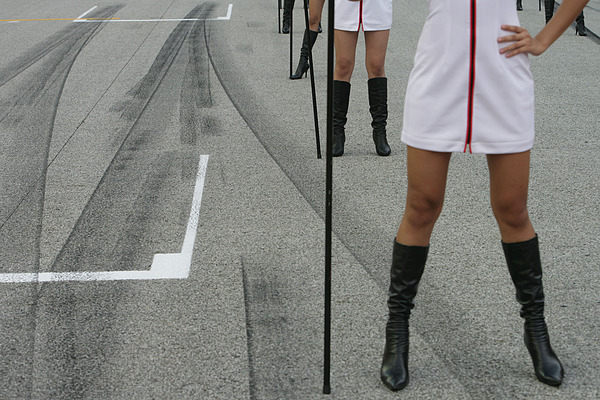 Die Grid-Girls stehen trotz Hitze in hohen Stiefeln auf den Spuren vergangener Rennstarts und ...