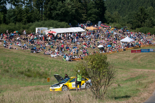 Image: An Opel Astra from the front car group stopped due to fuel pump damage. In the background the large spectator area of Steiningen - Eifel Rallye Festival 2013