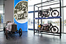 Exponate aus der Sonderausstellung „Der fünfte Ring“ im Audi museum mobile: Das Foto im Hintergrund zeigt Gertrude Eisemann – die „Meisterin des Motorrads“ – auf einem 2-PS-NSU-Motorrad. (© AUDI AG, 2022) Exponate aus der Sonderausstellung „Der fünfte Ring“ im Audi museum mobile: Das Foto im Hintergrund zeigt Gertrude Eisemann – die „Meisterin des Motorrads“ – auf einem 2-PS-NSU-Motorrad. (© AUDI AG, 2022)