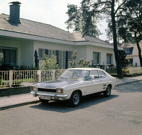 Spiessigkeit und Sportlichkeit: ein Capri 1700 GT XLR mit Rallye-Lackierung vor einem Bungalow 1972