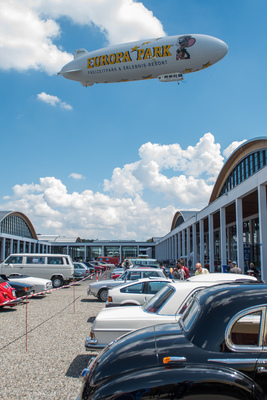 Bild: Ganz nach dem Motto der Messe: "zu Wasser, zu Lande und in der Luft" - Zeppelin überflog den grossen Innenplatz der Messe Friedrichshafen, wo etliche Besucher ihre Oldtimer abstellten - Motorworld Classics Bodensee 2018