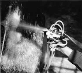 Hier wird die zerkleinerte Kunstfaser bei der Porsche-904-Karosserie mit einer Pistole aufgespritzt. Die Pistole hat je eine Düse für Polyesterharz, Kunstfaser und Härter.