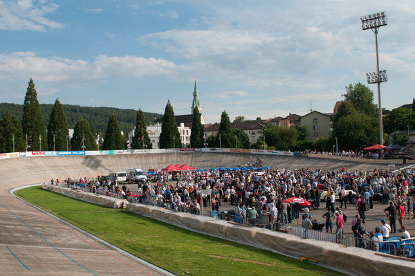 Im Innenfeld der Rennbahn Oerlikon werden die historischen Rennwagen unter die Lupe genommen während ein Radrennen startet - Indianapolis in Oerlikon 2014