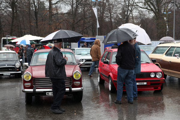Impressionen vom Oldtimer- und Teilemarkt Fribourg 2014 - Interessierte Käufer schauen sich die Fahrzeuge auf dem Freigelände im Schutz von Schirmen an