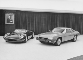 Jaguar XJ-S (1975) – William Lyons, damals ein noch durchaus rüstiger Pensionär, schien nicht abkömmlich also hat man kurzerhand sein Bild zum XJ13 und dem neuen XJ-S hinzu gehängt (1975)