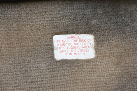 Die Plakette ermahnt, dass der Raum hinter den Sitzen nur zur Gepäck- und nicht zur Personenbeförderung gedacht ist