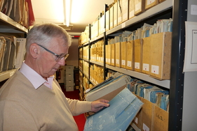 John zieht eine der Blaupausen heraus. Es scheint sich auf den ersten Blick um die Zeichnung einer Öl- oder Bremsleitung zu handeln