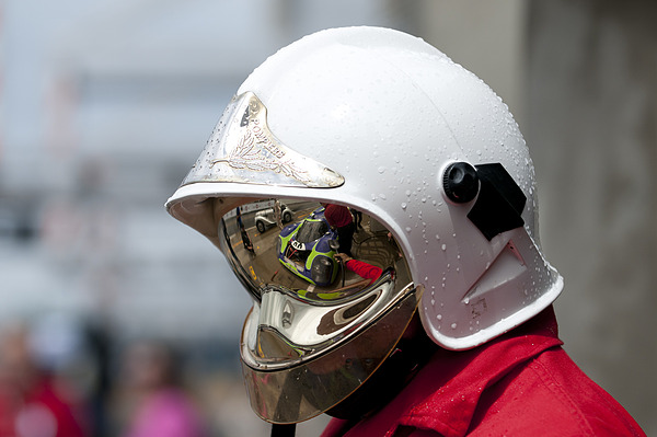 Image: Le Mans Classic 2012 - The famous Porsche 917 chassis 021 in the mirrored visor of a pit lane pompier (fireman)