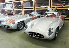 Das "rote" Coupé im Lager der Mercedes-Benz-Sammlung. Neben ihm steht eines der nie eingesetzten 1956er Modelle, erkennbar an der Motorhaube, mit der Startnummer von Fangios 1955er Mille-Miglia-Wagen.
