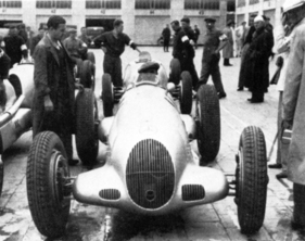 Zwei Mercedes-Benz W25K nahmen am Eifelrennen über 10 Runden auf dem Nürburgring teil. Einen davon fuhr Hermann Lang, der hier im Fahrerlager der Strecke zu sehen ist.