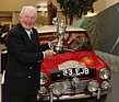 Bild: Mini Cooper S (1964) - Paddy Hopkirk mit seinem damaligen Pokal an der Rallye Monte Carlo