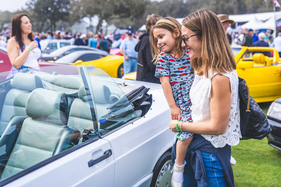 Mitleidiges Lächeln: die Kleidung zeigt, für welche Autos sich die junge Dame mehr interessiert als für den offenen 190E – The Amelia Concours d'Elegance 2024