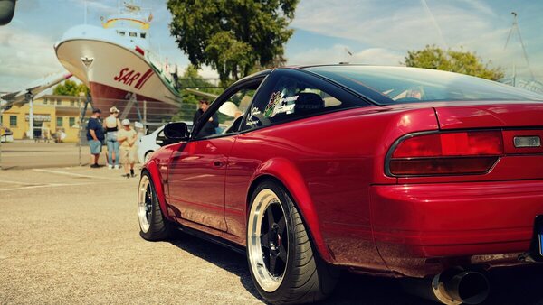 Nissan 200SX (S13) (1992) - Die Heckleuchten laufen als Band über die ganze Breite, dahinter ein Seenotrettungskreuzer auf dem Trockenen