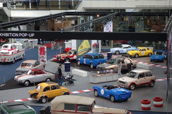 Ölfässer, Reifenstapel und rot-weisse Randsteine betonen den Motorsportbezug – Ausstellung "75 Jahre Abarth" in der Autoworld Brüssel