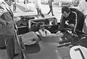 Peter Revson wird in seinen #7 Alfa Romeo 33/TT/3 eingepasst. Der technische Manager Gherardo Severi von Autodelta (rechts) gibt dazu Instruktionen