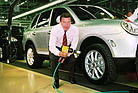 Bild: Porsche Cayenne (2002) - Die Gäste der offiziellen Einweihung der „Porsche Leipzig GmbH“, unter ihnen der deutsche Bundeskanzler Gerhard Schröder, erleben am 20. August eine Überraschungspräsentation des Porsche Cayenne noch vor der offiziellen Weltpremiere