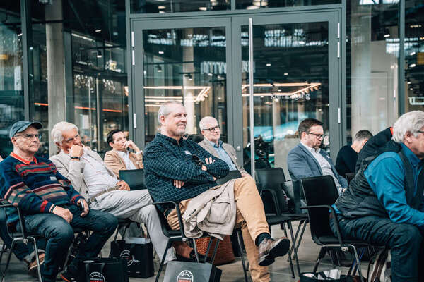Image: Audience seated in a semicircle—the Motorworld tote bags containing the book award materials are stored under the seats