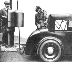 Rover Scarab (1931) – mit aufgespanntem Verdeck an der Tankstelle. Per "Fallbenzin" gespeist, hat der Motor keine Kraftstoffpumpe