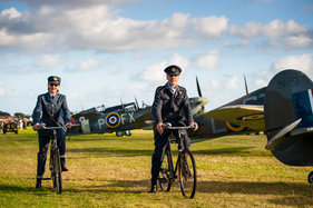 Spitfires mit authentisch bekleideten  Radfahrern - Impressionen vom Goodwood Revival 2015
