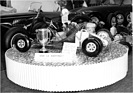 Swisskart (1964) - Vive le Karting - Rennkart, ausgestellt auf einem Kuchenblech - dahinter der Stand von Morgan - Genfer Automobilsalon 1964