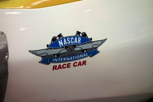 Verspieltes NASCAR-Wappen mit geflügelten Autos – Essen Motor Show 2023