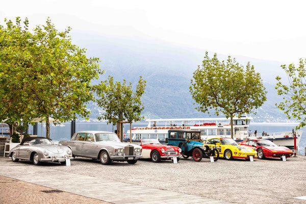 Diversity on the Lungolago—a Porsche 356 Cabriolet and a Rolls-Royce sedan alongside an open-top roadster and a pre-war car, set against the backdrop of Lake Maggiore
