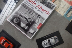 Vitrine mit Schaustücken inklusive des Buchs von Anneliese Abarth – Ausstellung "75 Jahre Abarth" in der Autoworld Brüssel Vitrine mit Schaustücken inklusive des Buchs von Anneliese Abarth – Ausstellung "75 Jahre Abarth" in der Autoworld Brüssel
