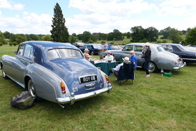 Zwei Exemplare des Rolls-Royce Silver Cloud III, einer aus dem Jahr 1963, der andere von 1965, rahmen eine feine Gesellschaft ein, die ein Gläschen Champagner genießt