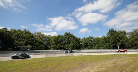 Zwei Jaguar Limousinen vor einem MG B im Karussell